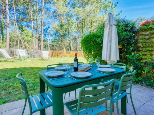 einem grünen Tisch mit einem Sonnenschirm und Stühlen in der Unterkunft Holiday Home Domaine Golf Resort-2 by Interhome in Lacanau-Océan