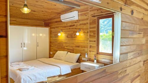a bedroom with a bed in a wooden wall at Jasmin Pansiyon Çıralı in Cıralı