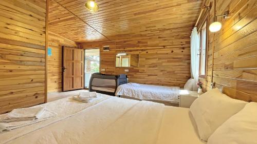 a bedroom with two beds and a wooden wall at Jasmin Pansiyon Çıralı in Cıralı