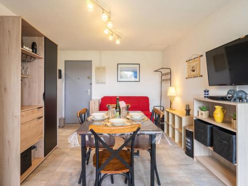 uma sala de jantar com uma mesa e um sofá vermelho em Apartment Les Balcons de l'Atlantique-12 by Interhome em Pontaillac