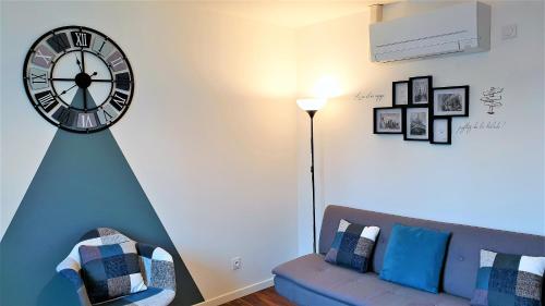 a living room with a couch and a clock on the wall at Joli F2 plein centre coté gare-Vélo-Climatisation in Migennes
