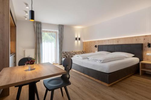 a bedroom with a large bed and a wooden table at Zur Brücke in Mittewald - Your home in heart of South Tyrol, with Brixencard and free parking, ideal starting point for unforgettable excursions and outdoor adventures in Fortezza