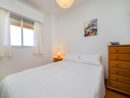 sypialnia z białym łóżkiem, komodą i oknem w obiekcie Apartment Voramar-5 by Interhome w mieście Calpe