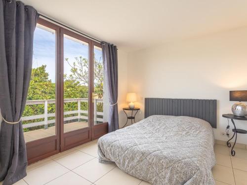 a bedroom with a bed and a balcony at Villa Les Pesquiers by Interhome in Hyères