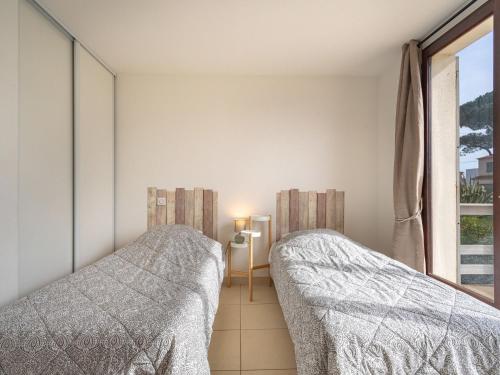 two beds in a bedroom with a window at Villa Les Pesquiers by Interhome in Hyères