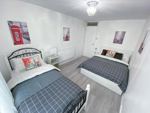 a bedroom with two beds and a chandelier at 2 Bed Flat, Dalston Junction, London in London