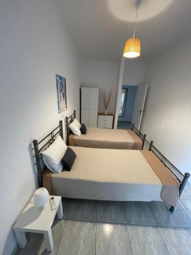 a room with two beds and a table and a lamp at Elenas Apartments in Plataria