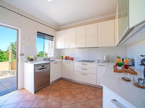 a kitchen with white cabinets and a large window at Holiday Home Casa do Sol by Interhome in Patroves