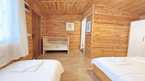 a room with two beds and a crib in it at Jasmin Pansiyon Çıralı in Cıralı