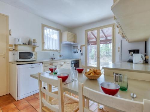 une cuisine avec une table et des chaises et une cuisine avec un comptoir dans l'établissement Holiday Home Les Sylvaines by Interhome, à Carcans