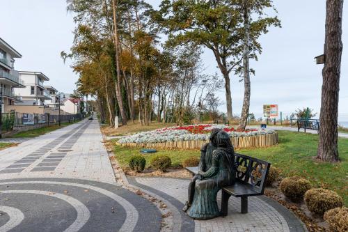 a statue of two people sitting on a bench at Klifowa Resort with SPA, Fitness & Kids Club by Renters in Rewal