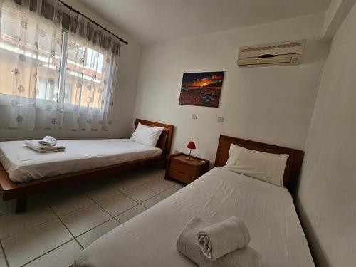 1 dormitorio con 2 camas y ventana en Iris Village, en Pafos