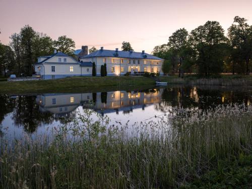 uma casa grande com um lago em frente em Padise Manor & Spa Boutique hotel - Adults Only em Padise