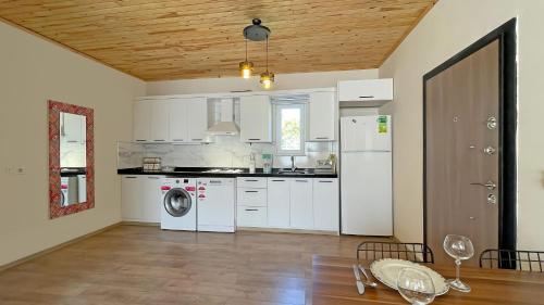 a kitchen with white appliances and a wooden ceiling at Jasmin Pansiyon Çıralı in Cıralı