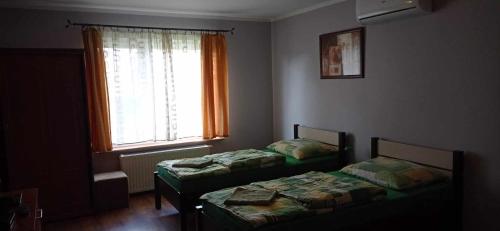 two beds in a room with a window at Zajazd U Doktora in Lubrza