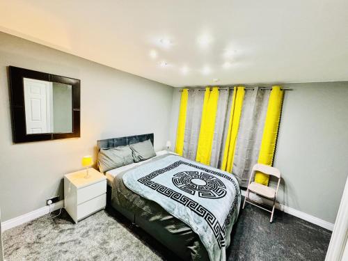 a bedroom with a bed and a mirror and yellow curtains at 4-Bed Full House Stourbridge Birmingham in Stourbridge