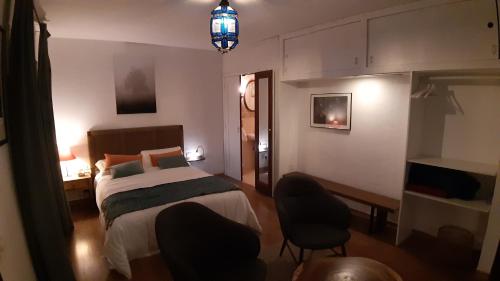 a bedroom with a bed and two chairs in it at Habitación con balcón y baños privados. in Tacoronte