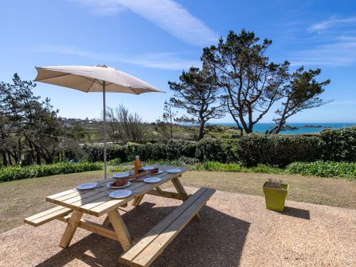 a picnic table with an umbrella and food on it at Holiday Home La maison de Toul an Dour by Interhome in Plouarzel