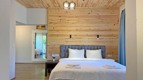 a bedroom with a large bed with a wooden wall at Jasmin Pansiyon Çıralı in Cıralı