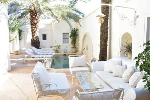 um pátio com mobiliário branco e uma piscina em Dar Shams em Erriadh