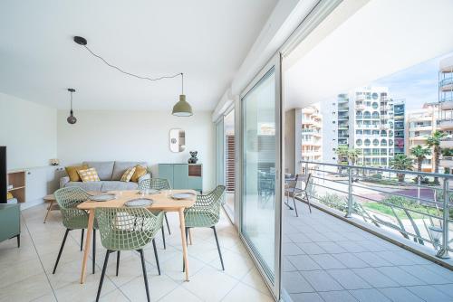 un salon avec une table et des chaises dans l'établissement L'Oiseau Bleu - Vue mer montagne, 100m de la plage, à Canet