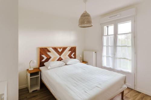 a white bedroom with a large bed and a window at Confort & Charme, proche Disney in Serris