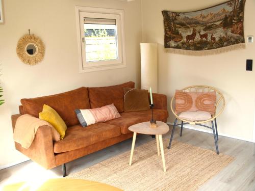 un soggiorno con divano marrone e tavolo di Gezellig gemoderniseerd chalet op de Veluwe a Putten