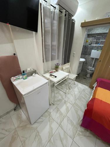 uma pequena cozinha branca com um lavatório e uma mesa em Ano Poli Studios 4 em Tessalónica