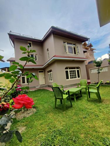 a house with chairs and a table in the yard at Home Away From Home Cute 3 bedroom House G floor in Srinagar