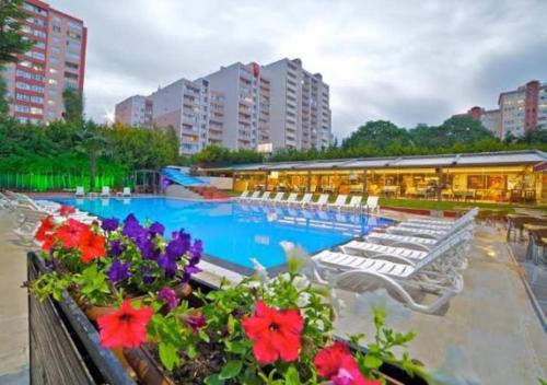 a swimming pool with white lounge chairs and flowers at Gardan Hotel in Beylikduzu