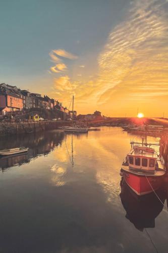 a boat is docked in the water at sunset at Apartment Lighthouse View by Interhome in Mevagissey