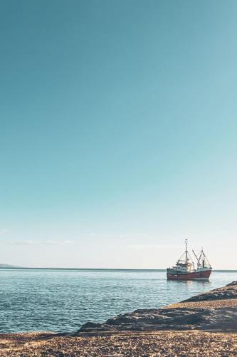 a boat sitting in the water next to a beach at Apartment Lighthouse View by Interhome in Mevagissey