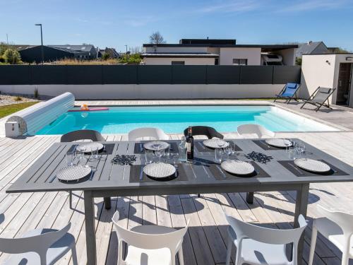 - une table et des chaises sur une terrasse à côté de la piscine dans l'établissement Holiday Home Au Gré du Vent by Interhome, à Brignogan-Plage