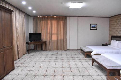 a hotel room with two beds and a television at Sunjin Grand Hotel in Ulaanbaatar