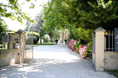 アヴィニョンにあるMas Château Blancの門と花を持って歩道を歩く者