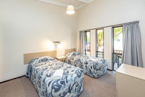 Habitación de hotel con 2 camas y ventana en Riverside Motel, en Whanganui