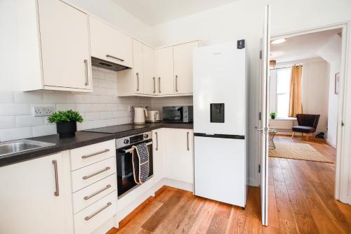 uma cozinha com armários brancos e pisos em madeira em St Marks House, Easton, Great Location, Free Parking em Bristol