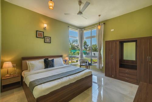 a bedroom with a large bed and a television at SaffronStays Caramelo - a private heated swimming pool villa with Jacuzzi nestled amidst beautiful landscaping and gardens in Lavasa in Lavasa