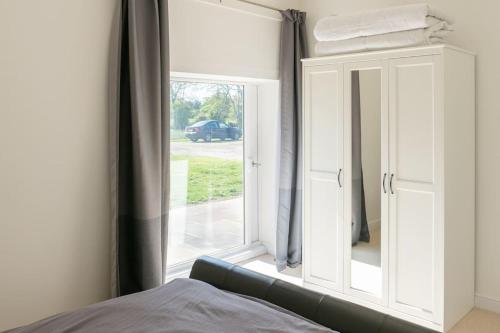 a bedroom with a large window and a couch at Long Range 1, Henham Park Nr Southwold in Beccles