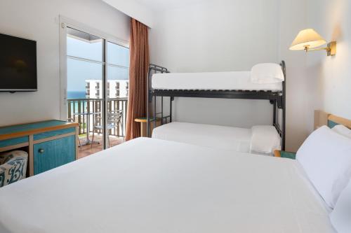 a bedroom with two beds and a tv and a balcony at Sol Milanos Pingüinos in Son Bou