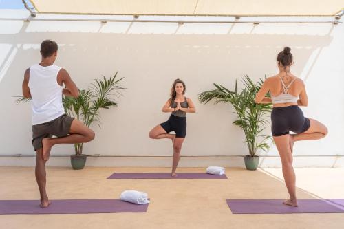 a group of people doing yoga in a yoga class at Sol Milanos Pingüinos in Son Bou