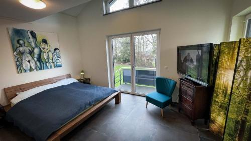 1 dormitorio con 1 cama, TV y silla en ANDERSWELTENlodge en Stipshausen
