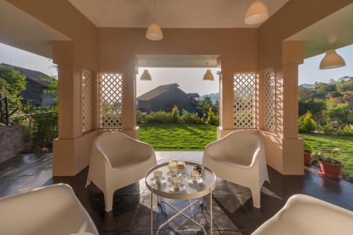 a living room with chairs and a glass table at SaffronStays Caramelo - a private swimming pool villa nestled amidst beautiful landscaping and gardens in Lavasa in Lavasa