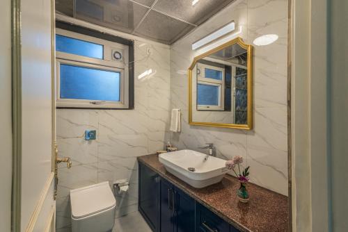 a bathroom with a sink and a toilet and a mirror at SaffronStays Caramelo - a private heated swimming pool villa with Jacuzzi nestled amidst beautiful landscaping and gardens in Lavasa in Lavasa