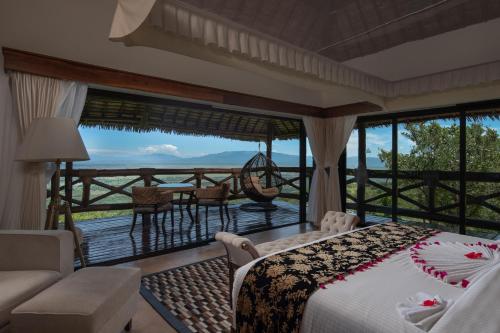 a bedroom with a bed and a balcony with a view at Lake Manyara Kilimamoja Lodge in Mto wa Mbu