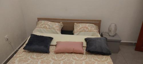 a bed with three pillows on it in a room at Lola Appartements 1 in Kribi