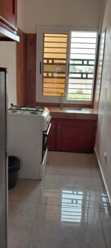 een keuken met een fornuis, een wastafel en 2 ramen bij Lola Appartements 1 in Kribi