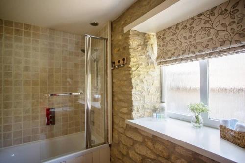 a bathroom with a shower and a window at Wishbone Cottage In The Cotswolds in Fairford