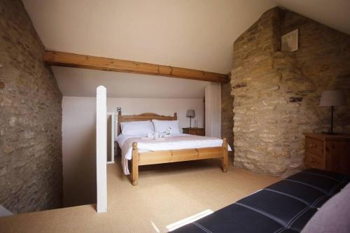 a bedroom with a bed and a stone wall at Wishbone Cottage In The Cotswolds in Fairford