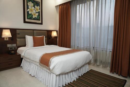 a bedroom with a large bed and a window at The Alcor Hotel in Jamshedpur